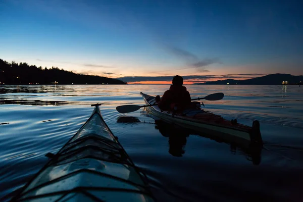 Man Kayaking on a sea kayak during a vibrant sunset. Taken near Jericho Beach, Vancouver, British Columbia, Canada.