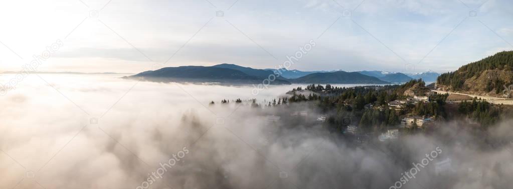 Aerial panoramic view of fog covered luxury homes on top of a hill. Taken in Horseshoe Bay, West Vancouver, British Columbia, Canada.