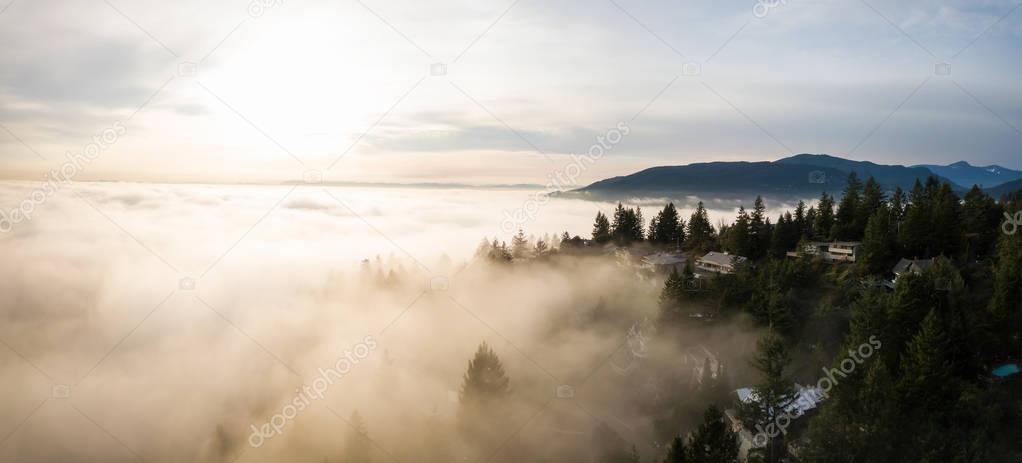 Aerial panoramic view of fog covered luxury homes on top of a hill. Taken in Horseshoe Bay, West Vancouver, British Columbia, Canada.