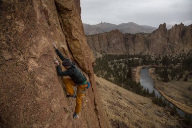 Maceracı biri rock sarp bir uçurum kenarında bir bulutlu kış gece boyunca tırmanma. Smith Rock, Oregon, Kuzey Amerika'da alınan.