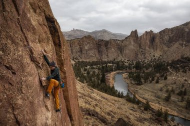 Maceracı biri rock sarp bir uçurum kenarında bir bulutlu kış gece boyunca tırmanma. Smith Rock, Oregon, Kuzey Amerika'da alınan.