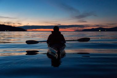 Adam kanosu canlı bir gün batımı sırasında deniz kayağı üzerinde. Alınan Jericho Beach, Vancouver, British Columbia, Kanada.