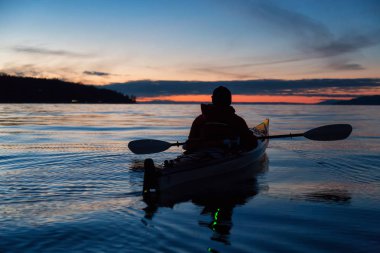 Adam kanosu canlı bir gün batımı sırasında deniz kayağı üzerinde. Alınan Jericho Beach, Vancouver, British Columbia, Kanada.