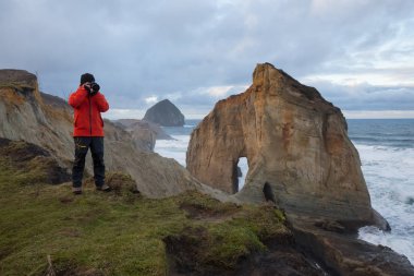 Fotoğrafçı Oregon kıyılarında Deniz kenarındaki güzel görünümü fotoğrafını çekmek. Cape Kiwanda, Pacific City, bulutlu kış sunsrise sırasında alınan.