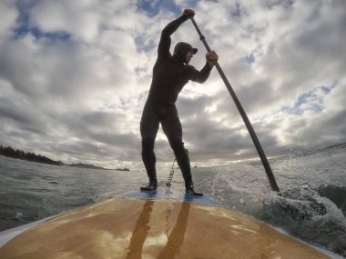Adam bir stand-up kürek tahtada okyanusta kürek çekmeye. Estevan, Vancouver Adası, British Columbia, Kanada alınan.