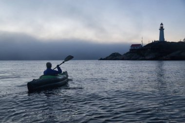 Deniz kayağı bir deniz fenerinde bir canlı ve sisli kış günbatımı sırasında maceracı kadındır. Horseshoe Bay, Batı Vancouver, Bc, Kanada çekilmiş. Konsept: Macera, tatil, tatil, keşfetmek