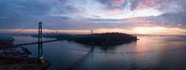Aerial panoramic view of a famous landmark, Lions Gate Bridge, with downtown city skyline in the background during a vibrant sunset. Taken in Vancouver, British Columbia, Canada. clipart