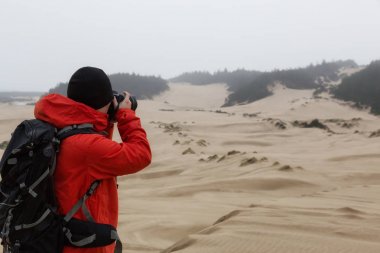 Photographer taking pictures of the beautiful landscape. Taken in Oregon Dunes National Recreation Area, Reedsport, Oregon Coast, USA. clipart