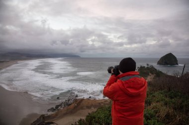 Fotoğrafçı Oregon kıyılarında Deniz kenarındaki güzel görünümü fotoğrafını çekmek. Cape Kiwanda, Pacific City, bulutlu kış sunsrise sırasında alınan.