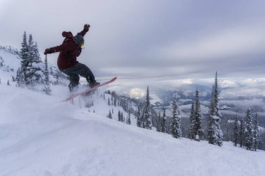 Snowboard karlı yamaç aşağı sırasında canlı ve bulutlu bir akşam biniyor. Revolstoke Ski Resort, British Columbia, Kanada çekilmiş. Macera, tatil kavramı