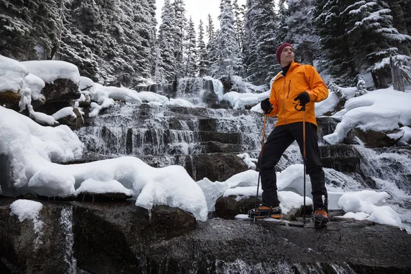 Adventure mNan standing besides a beautiful waterfall in the winter wilderness. Taken in Joffre Lakes, North of Vancouver, British Columbia, Canada. Concept: Adventure, holiday