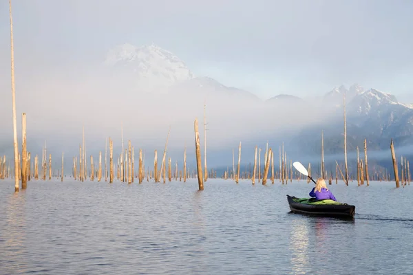 Adventurous girl is kayaking on an inflatable kayak on a beautiful lake with mountains in the background. Taken in Stave Lake, East of Vancouver, British Columbia, Canada.