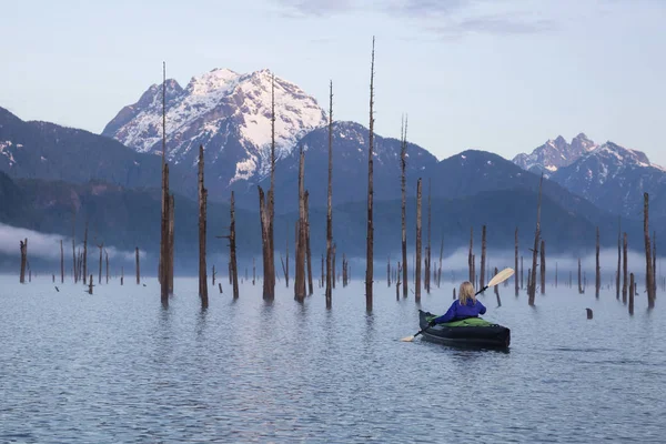 Adventurous girl is kayaking on an inflatable kayak on a beautiful lake with mountains in the background. Taken in Stave Lake, East of Vancouver, British Columbia, Canada.