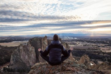 Maceracı bir meditasyon poz bir uçurumun üstünde canlı bir gün batımı sırasında oturan adam. Smith Rock, Oregon, Amerika'nın alınan. Konsept: Macera, özgürlük, seyahat, tatil, tatil
