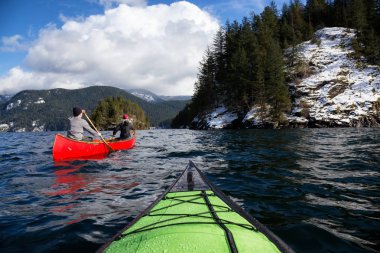 Ahşap bir Kano üzerinde çift arkadaşlar Kanada dağlarla çevrili bir giriş kürek çekmeye. Hint kol, Deep Cove yakınındaki kuzey Vancouver, British Columbia, Kanada çekilmiş.