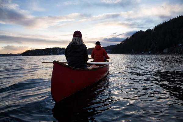 木製のカヌーにカップルの友人は 活気のある日没時にカナダの山々 に囲まれた入り江にパドリングが ノース バンクーバー ブリティッシュ コロンビア カナダ インドの腕 ディープ — ストック写真