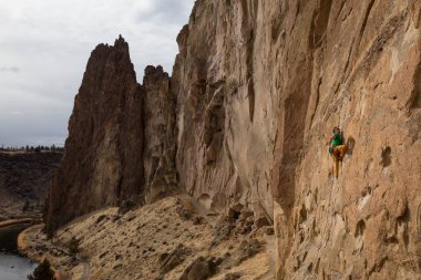 Maceracı biri rock sarp bir uçurum kenarında bir bulutlu kış gece boyunca tırmanma. Smith Rock, Oregon, Kuzey Amerika'da alınan.
