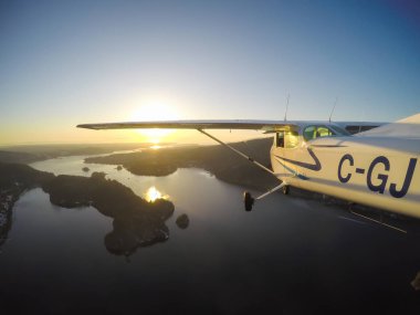 Vancouver, British Columbia, Kanada - 22 Şubat 2018: Küçük uçak, Cessna 172, canlı bir gün batımı sırasında şehrin üzerinde uçuyor.