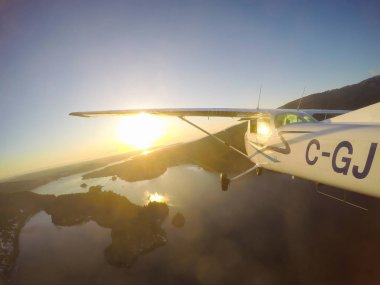 Vancouver, British Columbia, Kanada - 22 Şubat 2018: Küçük uçak, Cessna 172, canlı bir gün batımı sırasında şehrin üzerinde uçuyor.