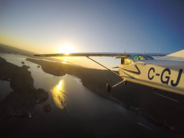 Vancouver, British Columbia, Kanada - 22 Şubat 2018: Küçük uçak, Cessna 172, canlı bir gün batımı sırasında şehrin üzerinde uçuyor.