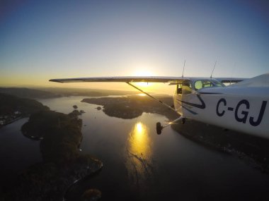 Vancouver, British Columbia, Kanada - 22 Şubat 2018: Küçük uçak, Cessna 172, canlı bir gün batımı sırasında şehrin üzerinde uçuyor.