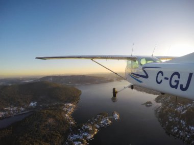 Vancouver, British Columbia, Kanada - 22 Şubat 2018: Küçük uçak, Cessna 172, canlı bir gün batımı sırasında şehrin üzerinde uçuyor.