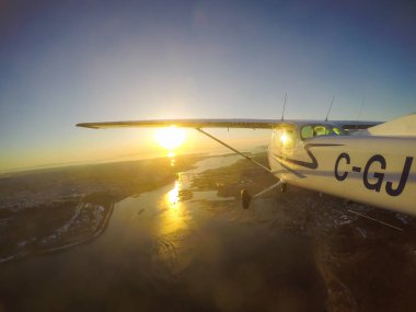 Vancouver, British Columbia, Kanada - 22 Şubat 2018: Küçük uçak, Cessna 172, canlı bir gün batımı sırasında şehrin üzerinde uçuyor.