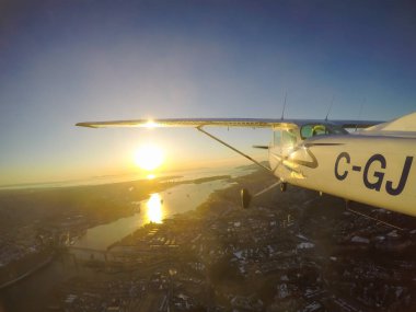 Vancouver, British Columbia, Kanada - 22 Şubat 2018: Küçük uçak, Cessna 172, canlı bir gün batımı sırasında şehrin üzerinde uçuyor.