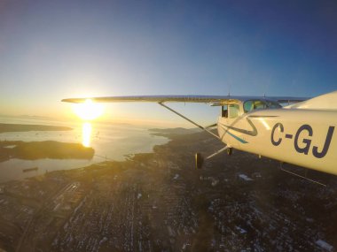 Vancouver, British Columbia, Kanada - 22 Şubat 2018: Küçük uçak, Cessna 172, canlı bir gün batımı sırasında şehrin üzerinde uçuyor.