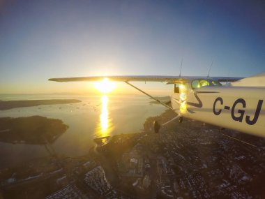 Vancouver, British Columbia, Kanada - 22 Şubat 2018: Küçük uçak, Cessna 172, canlı bir gün batımı sırasında şehrin üzerinde uçuyor.