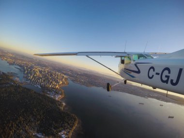Vancouver, British Columbia, Kanada - 22 Şubat 2018: Küçük uçak, Cessna 172, canlı bir gün batımı sırasında şehrin üzerinde uçuyor.