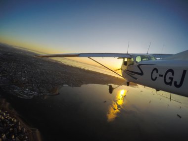 Vancouver, British Columbia, Kanada - 22 Şubat 2018: Küçük uçak, Cessna 172, canlı bir gün batımı sırasında şehrin üzerinde uçuyor.