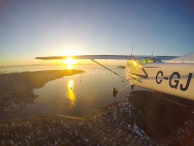 Vancouver, British Columbia, Kanada - 22 Şubat 2018: Küçük uçak, Cessna 172, canlı bir gün batımı sırasında şehrin üzerinde uçuyor.