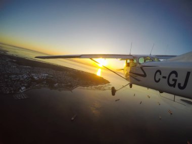 Vancouver, British Columbia, Kanada - 22 Şubat 2018: Küçük uçak, Cessna 172, canlı bir gün batımı sırasında şehrin üzerinde uçuyor.