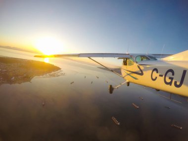 Vancouver, British Columbia, Kanada - 22 Şubat 2018: Küçük uçak, Cessna 172, canlı bir gün batımı sırasında şehrin üzerinde uçuyor.