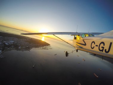 Vancouver, British Columbia, Kanada - 22 Şubat 2018: Küçük uçak, Cessna 172, canlı bir gün batımı sırasında şehrin üzerinde uçuyor.