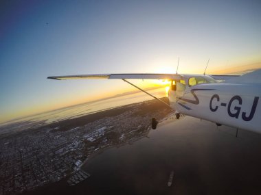 Vancouver, British Columbia, Kanada - 22 Şubat 2018: Küçük uçak, Cessna 172, canlı bir gün batımı sırasında şehrin üzerinde uçuyor.