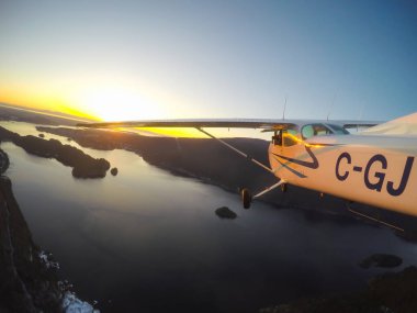 Vancouver, British Columbia, Kanada - 22 Şubat 2018: Küçük uçak, Cessna 172, canlı bir gün batımı sırasında şehrin üzerinde uçuyor.