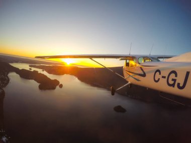 Vancouver, British Columbia, Kanada - 22 Şubat 2018: Küçük uçak, Cessna 172, canlı bir gün batımı sırasında şehrin üzerinde uçuyor.