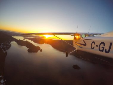 Vancouver, British Columbia, Kanada - 22 Şubat 2018: Küçük uçak, Cessna 172, canlı bir gün batımı sırasında şehrin üzerinde uçuyor.