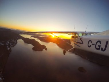Vancouver, British Columbia, Kanada - 22 Şubat 2018: Küçük uçak, Cessna 172, canlı bir gün batımı sırasında şehrin üzerinde uçuyor.