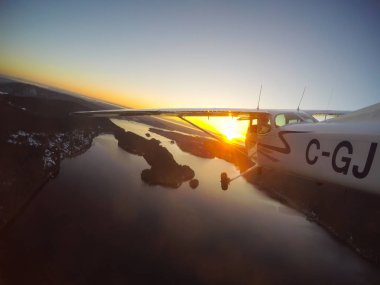 Vancouver, British Columbia, Kanada - 22 Şubat 2018: Küçük uçak, Cessna 172, canlı bir gün batımı sırasında şehrin üzerinde uçuyor.
