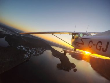 Vancouver, British Columbia, Kanada - 22 Şubat 2018: Küçük uçak, Cessna 172, canlı bir gün batımı sırasında şehrin üzerinde uçuyor.