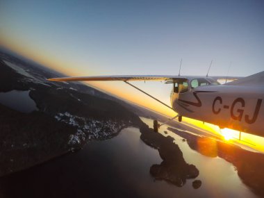 Vancouver, British Columbia, Kanada - 22 Şubat 2018: Küçük uçak, Cessna 172, canlı bir gün batımı sırasında şehrin üzerinde uçuyor.