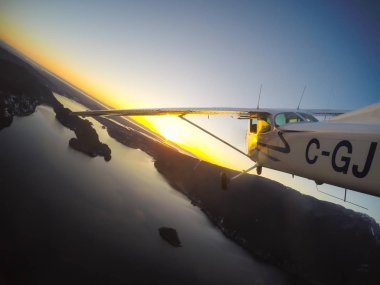 Vancouver, British Columbia, Kanada - 22 Şubat 2018: Küçük uçak, Cessna 172, canlı bir gün batımı sırasında şehrin üzerinde uçuyor.