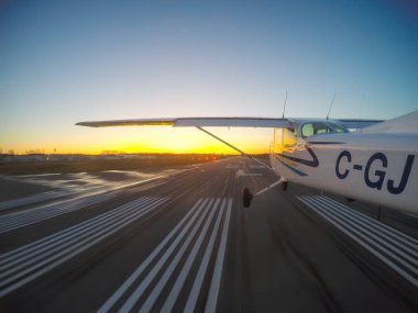 Vancouver, British Columbia, Kanada - 22 Şubat 2018: Küçük uçak, Cessna 172, canlı bir gün batımı sırasında podyumda iniyor.