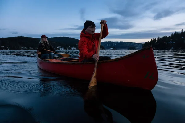 木製のカヌーにカップルの友人は 活気のある日没時にカナダの山々 に囲まれた入り江にパドリングが ノース バンクーバー ブリティッシュ コロンビア カナダ インドの腕 ディープ — ストック写真