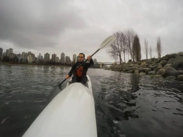 Man paddling on Surf Ski during a cloudy and rainy winter day. Taken in Vancouver, British Columbia, Canada.