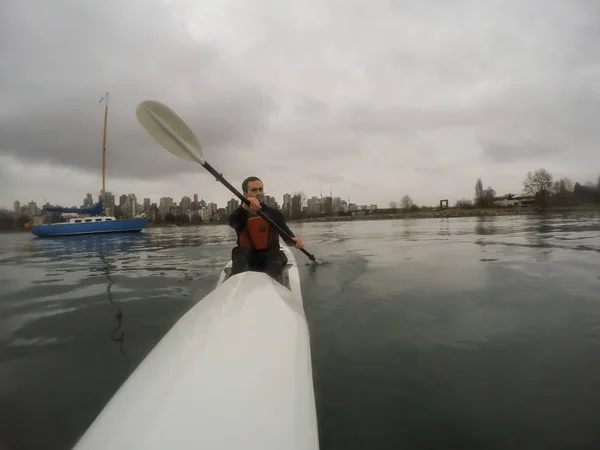 Man paddling on Surf Ski during a cloudy and rainy winter day. Taken in Vancouver, British Columbia, Canada.