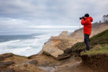 Maceracı bir kamera ile ayakta resimlerini güzel okyanus sırasında canlı kış sabahı adamdır. Cape Kiwanda, Pacific City, Oregon kıyılarında, Amerika'da alınan.